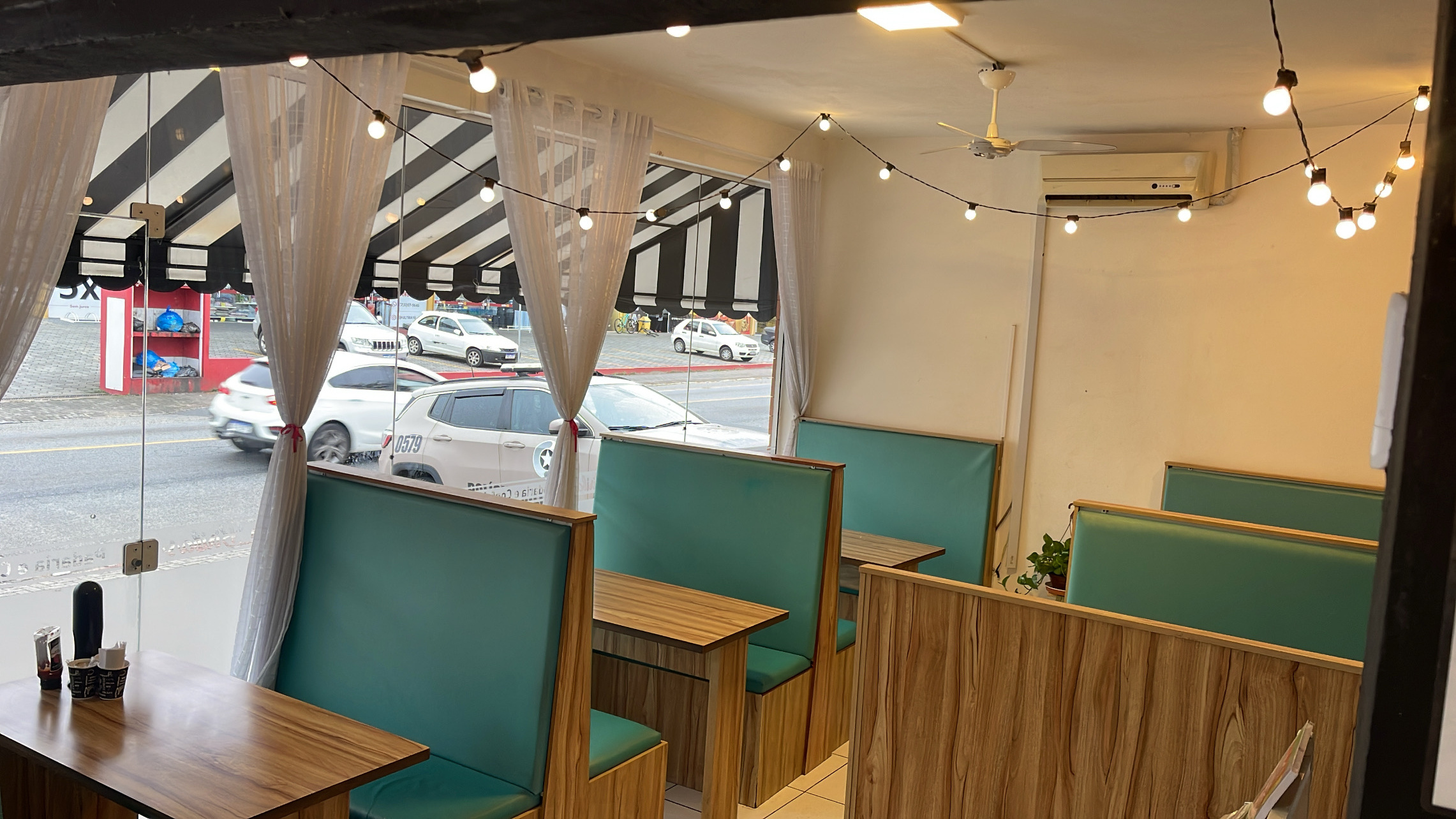 Interior da Biribas com mesas, divisórias e bancos
